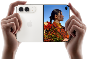 جهاز iPhone Duo، لون أبيض النجوم، يدان تحملان الجهاز في الوضع الأفقي، مفتوح، اللوحة اليسرى تعرض نظام كاميرا مزدوجة 48MP&nbsp;Fusion، اللوحة اليمنى تعرض شخصاً تُلتقط صورته على الشاشة الخارجية، يمكن لهذا الشخص رؤية وجهه لأن الصورة تُلتقط باستخدام ميزة Duo&nbsp;Preview‏